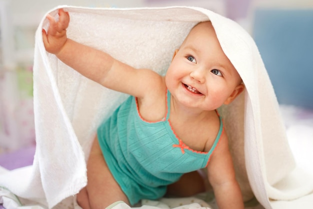 Bambino sorridente sveglio che guarda l'obbiettivo sotto un asciugamano bianco Ritratto di un bambino carino