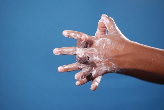 bambino squadrato che si lava le mani con il sapone su sfondo blu