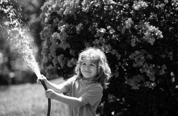 Bambino sta innaffiando la pianta fuori dalla casa concetto di coltivazione di piante attività di apprendimento per bambini