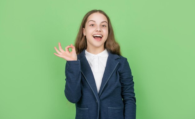 Bambino stupito con un gesto di saluto su sfondo verde