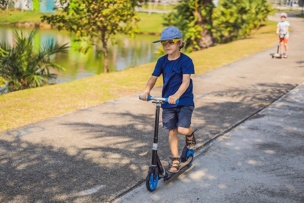 Bambino su monopattino nel parco i bambini imparano a pattinare sulla tavola a rulli ragazzino che pattina in estate soleggiata