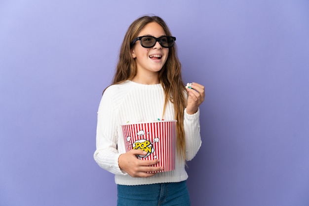 Bambino su sfondo viola isolato con occhiali 3d e con in mano un grande secchio di popcorn