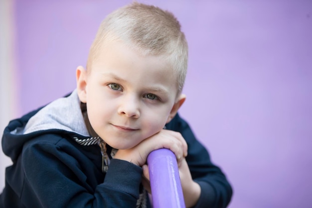 Bambino su sfondo viola Ragazzino biondo sorride