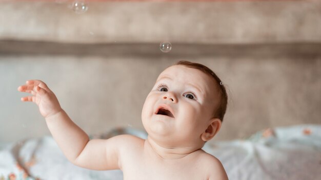 Bambino su un letto con bolle di sapone