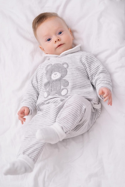 Bambino su un letto Vista dall'alto di adorabile bambino sul letto e guardando la fotocamera con curiosità vista dall'alto