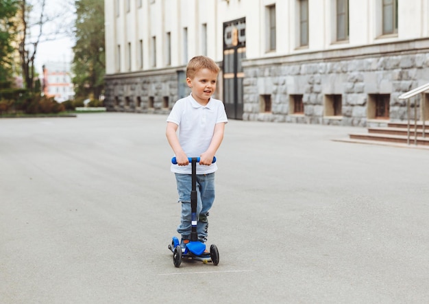 Bambino su uno scooter nel parco Un ragazzino guida uno scooter in una giornata di sole Sport attivi per bambini in età prescolare