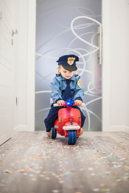 bambino su uno scooter rosso vestito da poliziotto