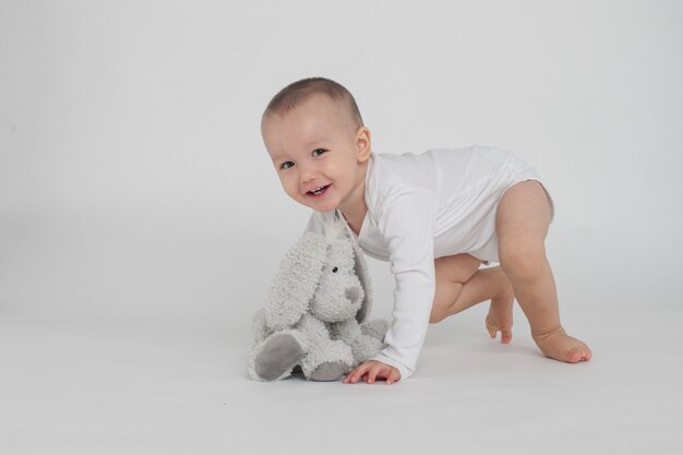 Bambino su uno sfondo bianco con un coniglietto di peluche