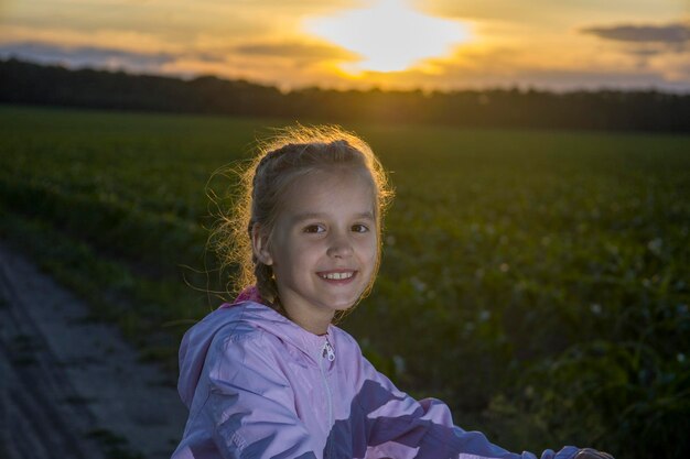 Bambino su uno sfondo di campo verde e con i raggi del sole della sera