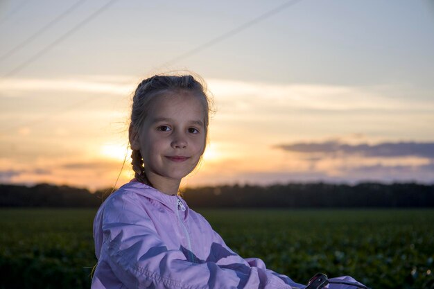 Bambino su uno sfondo di campo verde e con i raggi del sole della sera