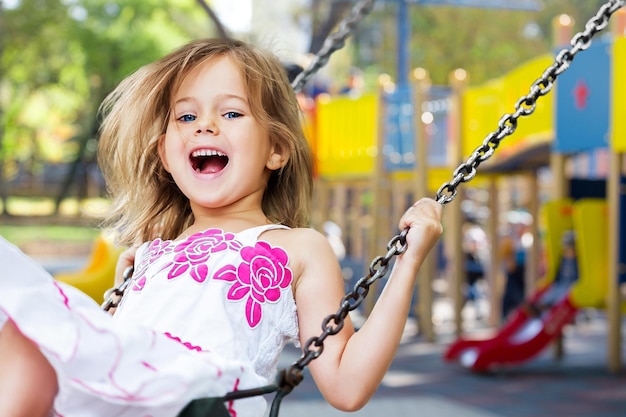 Bambino sull'altalena che gioca nel parco giochi all'aperto.