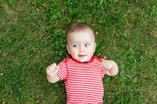 Bambino sull'erba o sul prato verde bambino che cammina fuori nel luogo estivo per il testo