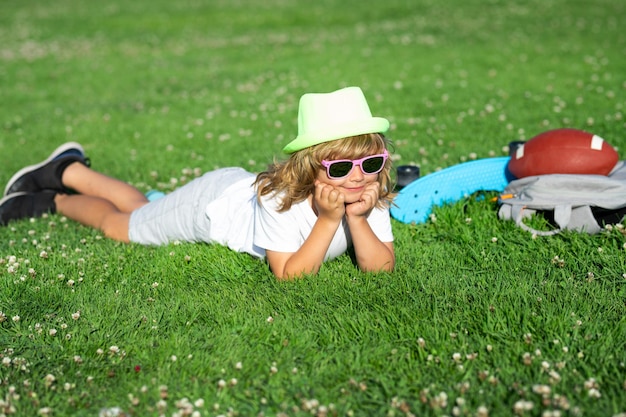 Bambino sulla natura ragazzo carino sdraiato sul prato bambino felice che gioca nel parco estivo