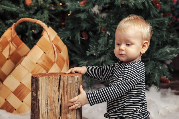 Bambino sulla soffice coperta bianca che gioca vicino all'albero di Natale