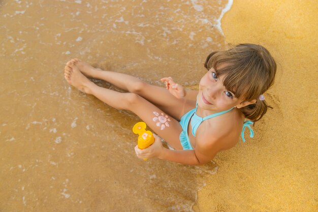 Bambino sulla spiaggia con crema solare sulla schiena.