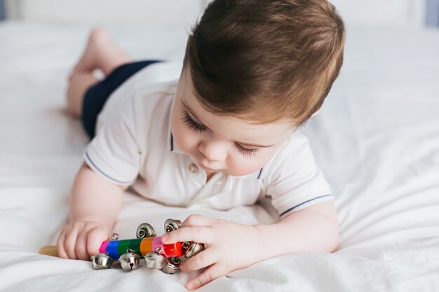 Bambino sveglio che gioca con il giocattolo sonaglio vintage pastello colorato.