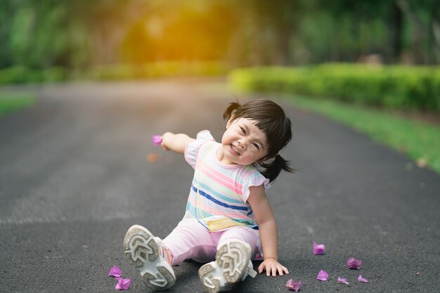 Bambino sveglio che si siede al giardino, concetto di attività all'aperto del bambino sveglio