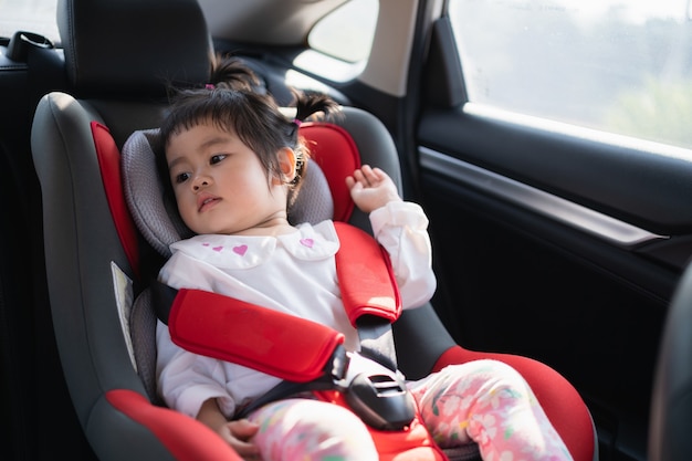 Bambino sveglio che si siede in un seggiolino auto