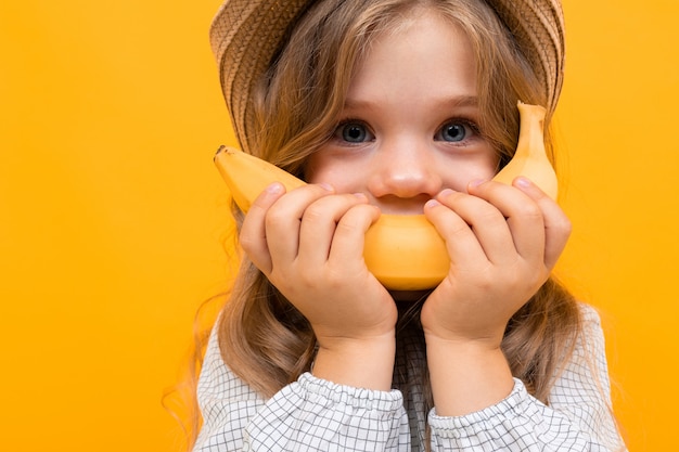 Bambino sveglio che tiene una banana invece di un sorriso, foto di una bella bambina