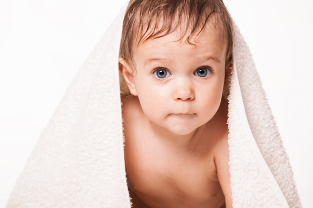 Bambino sveglio con l'asciugamano sulla testa e sugli occhi azzurri