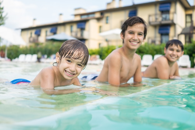 Bambino sveglio del bambino del ragazzino che spruzza nella piscina divertendosi attività di svago