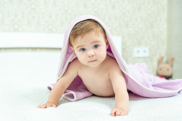 Bambino sveglio del bambino sotto un asciugamano con cappuccio dopo il bagno. Ritratto di bambini. concetto di assistenza sanitaria.