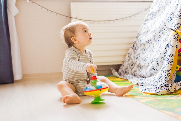 Bambino sveglio del neonato che gioca con il giocattolo all'interno