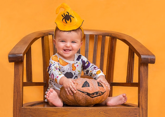 Bambino sveglio in cappello della strega che tiene una zucca