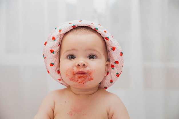 bambino sveglio in un cappello che mangia fragole a letto