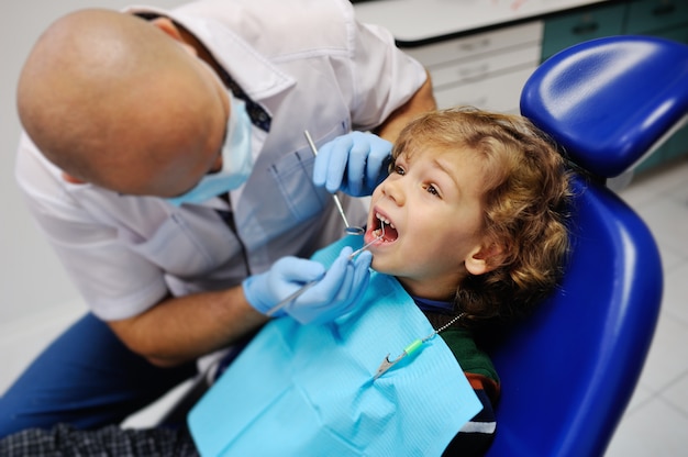 Bambino sveglio in un maglione a strisce alla reception dal dentista