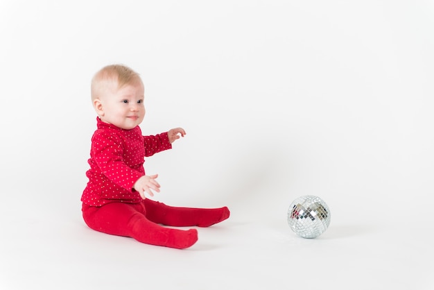 Bambino sveglio in vestito rosso che gioca con un pallone da festa