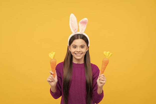 Bambino teenager allegro in orecchie da coniglio che tengono la festa di pasqua della carota