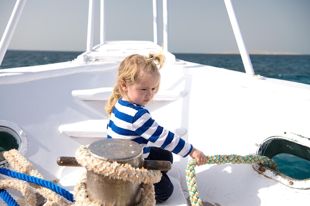 Bambino tirare la corda sullo yacht in una giornata di sole