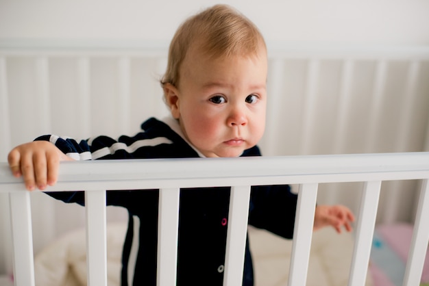 Bambino triste in piedi nella culla