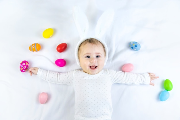 Bambino vestito come un coniglietto con le uova di Pasqua per le vacanze di Pasqua sulla superficie bianca