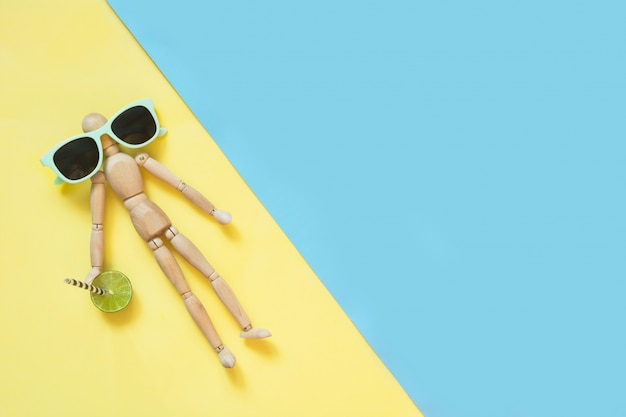 Bambola di legno con occhiali da sole su giallo. Uv protettivo.