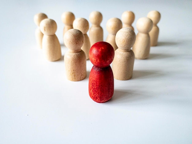 Bambola di legno rossa che guida il resto della figura di legno Concetto di leadership e seguaci