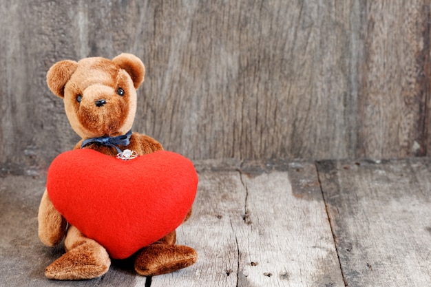 Bambola orso giocattolo e anello gioiello con cuore rosso.