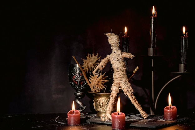 Bambola voodoo candele nere pentagramma e vecchi libri sul tavolo delle streghe Divinazione esoterica occulta e concetto di wicca Voodoo mistico e sfondo vintage