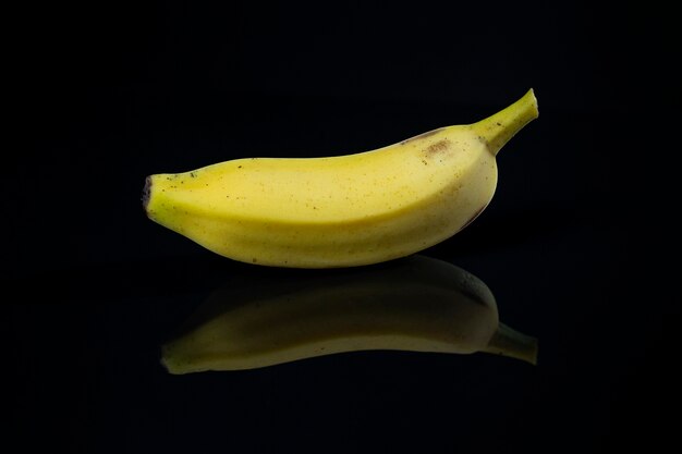 Banana con riflesso su base acrilica nera.