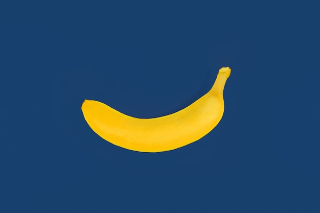 Banana di plastica gialla del giocattolo su fondo colorato blu