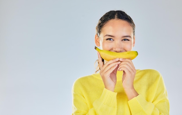 Banana felice e ritratto di donna con frutta in studio per un'alimentazione sana, benessere e dieta Il cibo perde peso e mockup persona su sfondo bianco con frutta per nutrizione disintossicazione e digestione