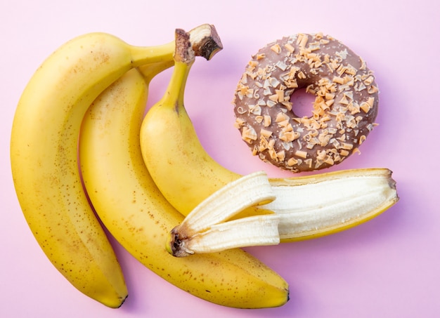 Banana gialla e ciambella su sfondo rosa. Sopra la vista