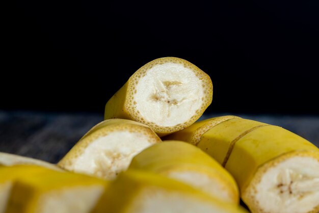 Banana gialla matura non sbucciata tagliata a pezzi su una tavola