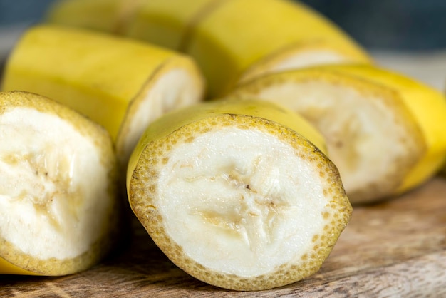 Banana gialla matura non sbucciata tagliata a pezzi su una tavola