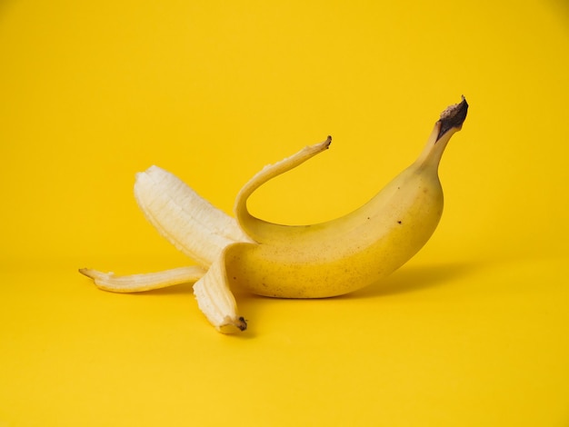 Banana sbucciata su sfondo giallo con spazio per la copia