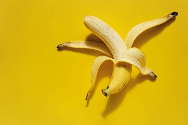 Banana sbucciata su sfondo giallo