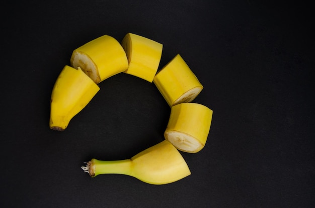 Banana su sfondo nero Concetto di cibo sano tagliare la banana gialla su un tavolo nero