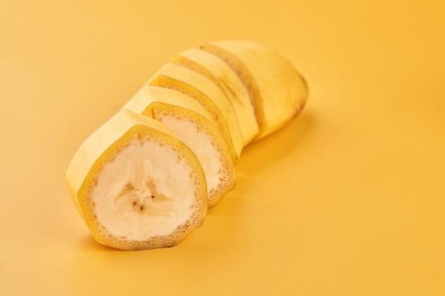 Banane affettate su fondo giallo da vicino, ingrediente da dessert sano