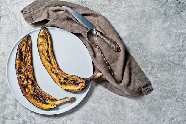 Banane al forno con miele su un piatto grigio.